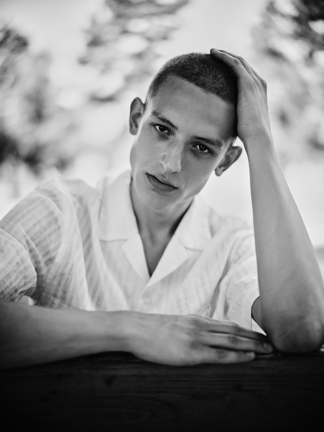 Aufnahme eines jungen Mannes der auf einer Parkbank sitzt