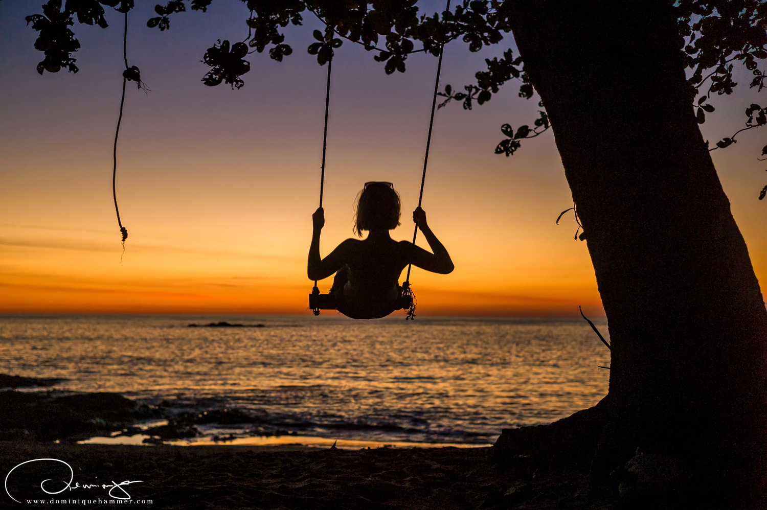 Eine junge Frau schaukelt am Strand von Khao Lak von Fotograf Dominique Hammer