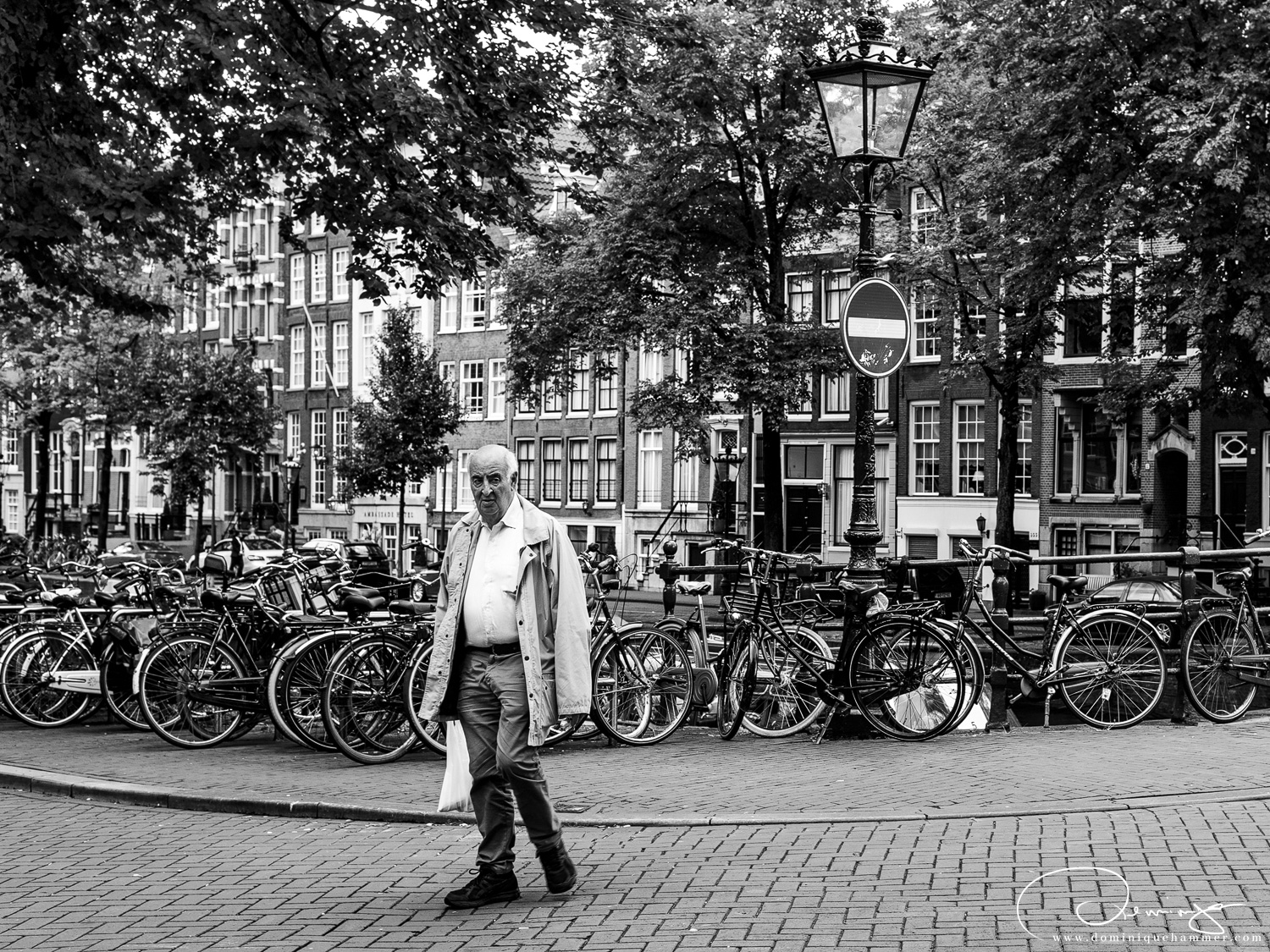 Ein Mann mit einem Einkaufssack auf einer Br&uuml;cke in Amsterdam von Fotograf Dominique Hammer