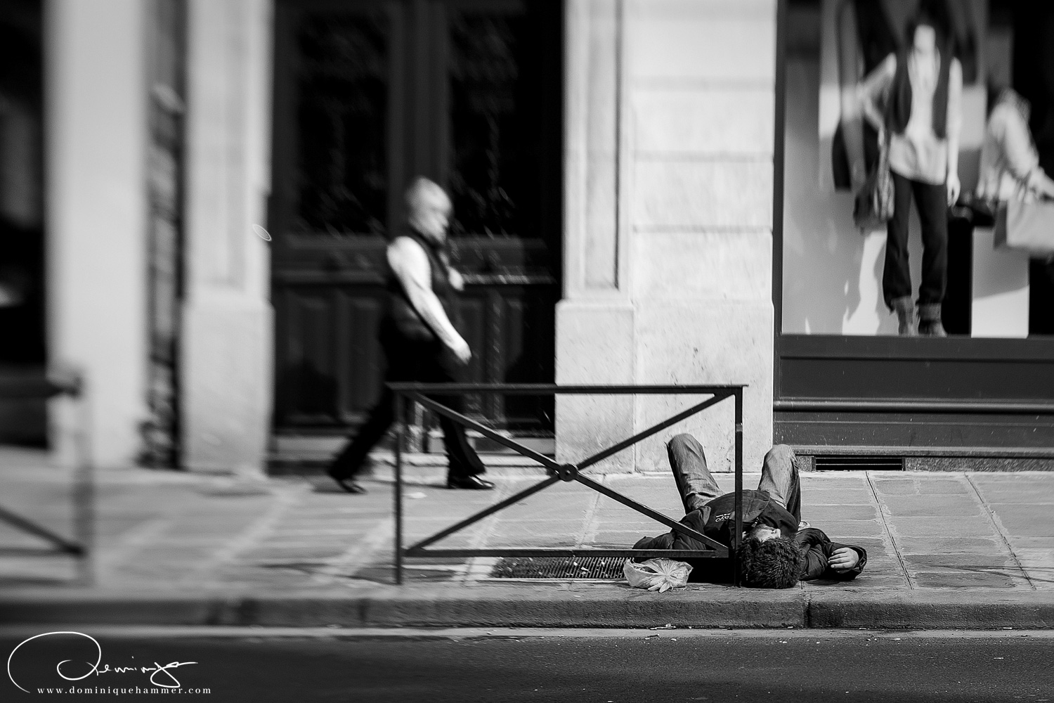 Ein Mann liegt betrunken auf der Stra&szlig;e in Paris, von Fotograf Dominique Hammer
